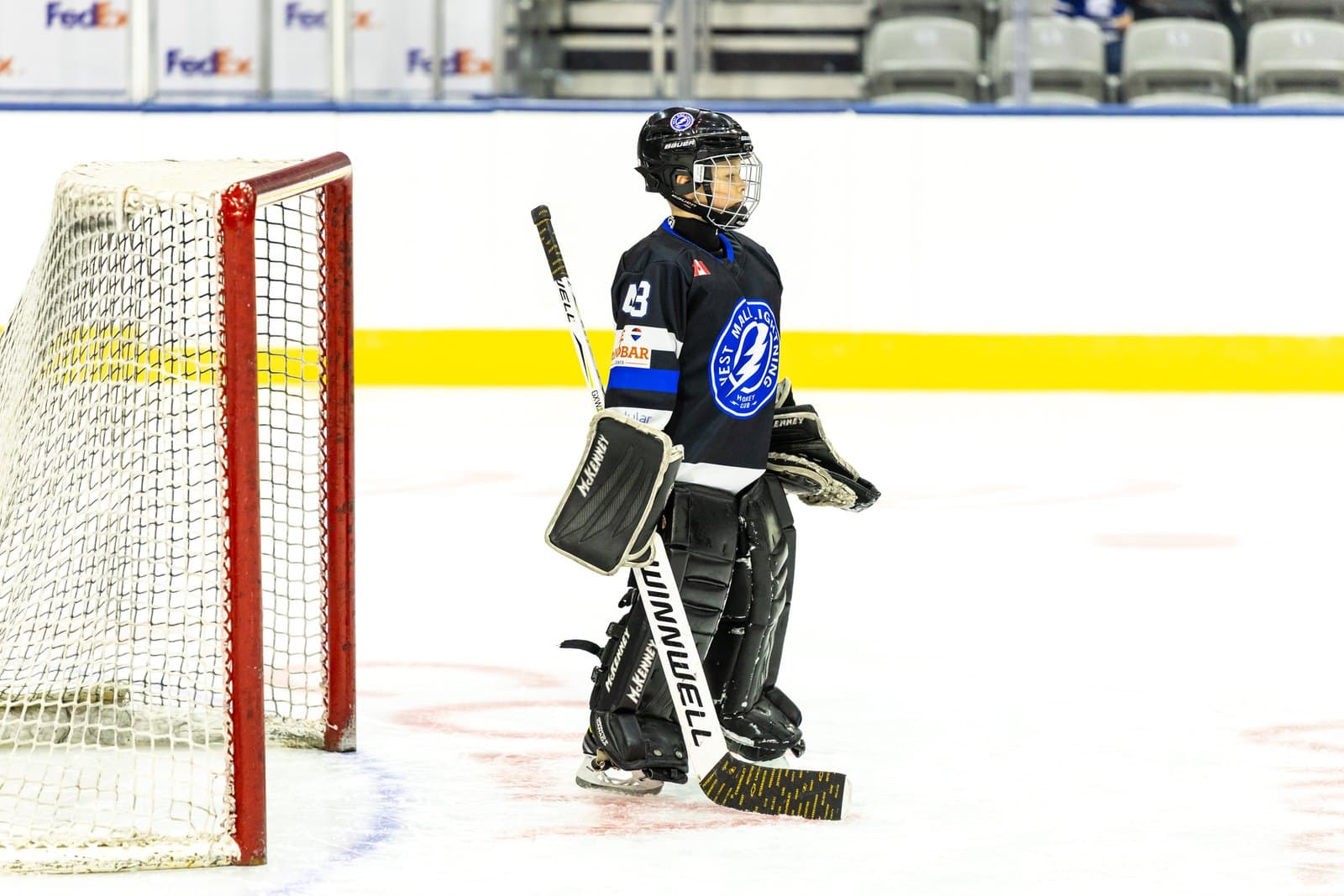 A young goaltender alone in the crease, stick down, waiting for the play