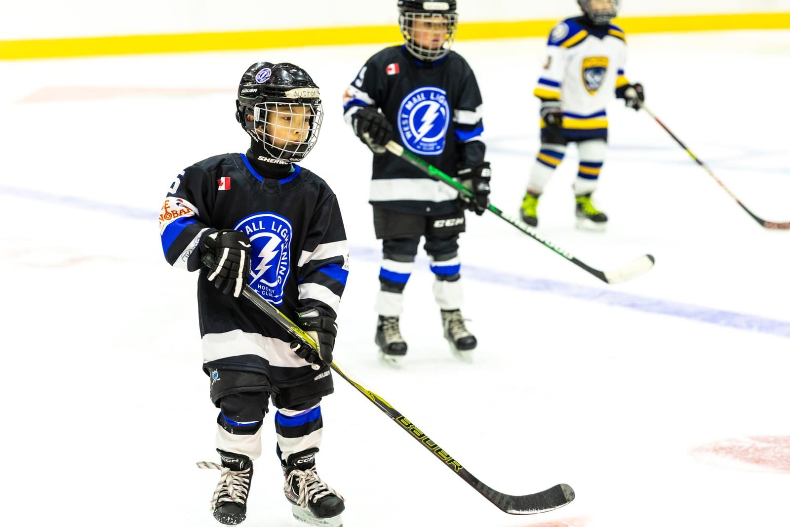 A skater carries the puck through centre ice with an opponent closing