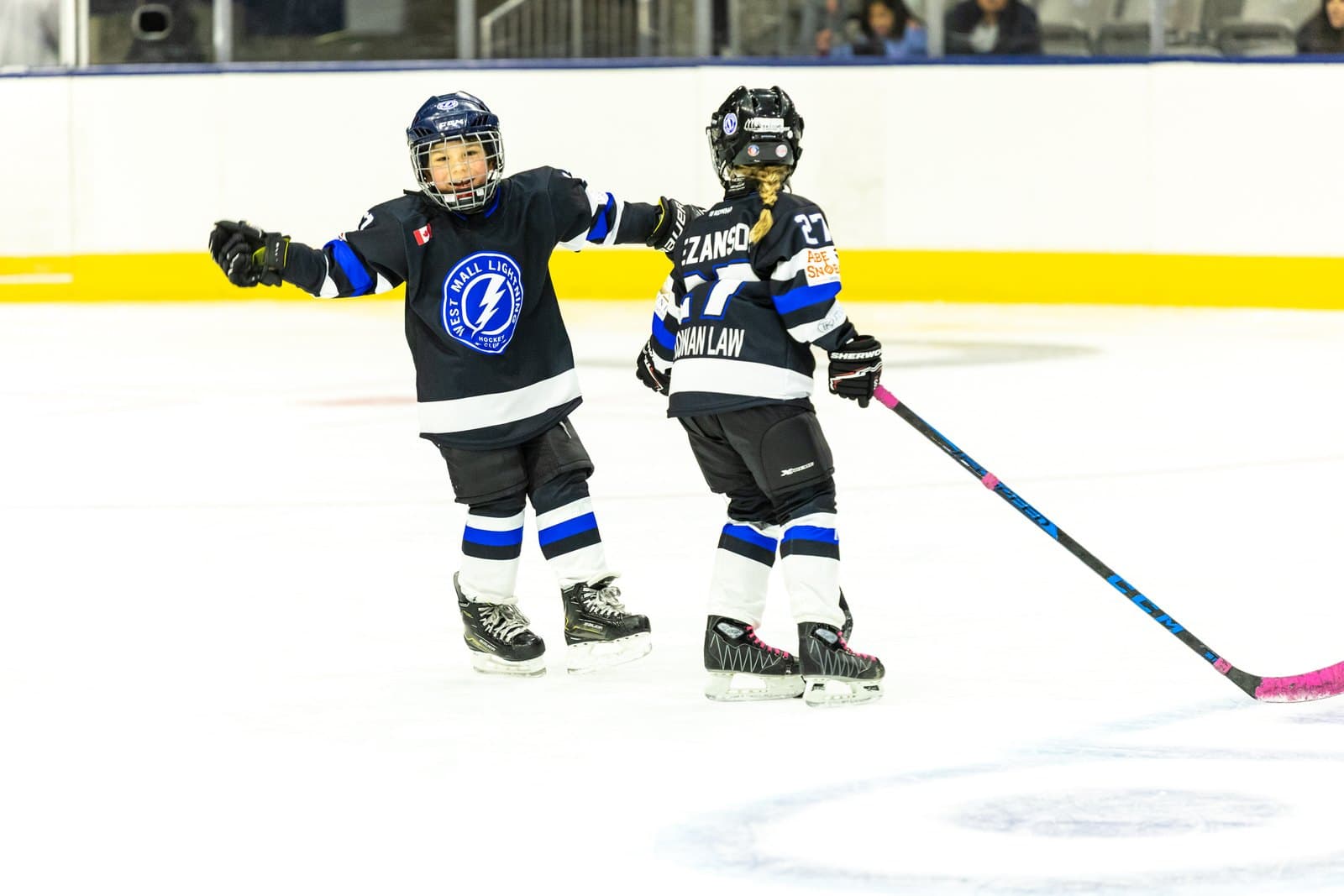 Two teammates skate together with arms out after the whistle