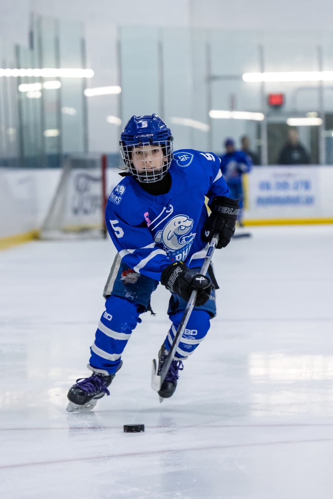 A skater bears down on a loose puck at full stride, eyes locked on it