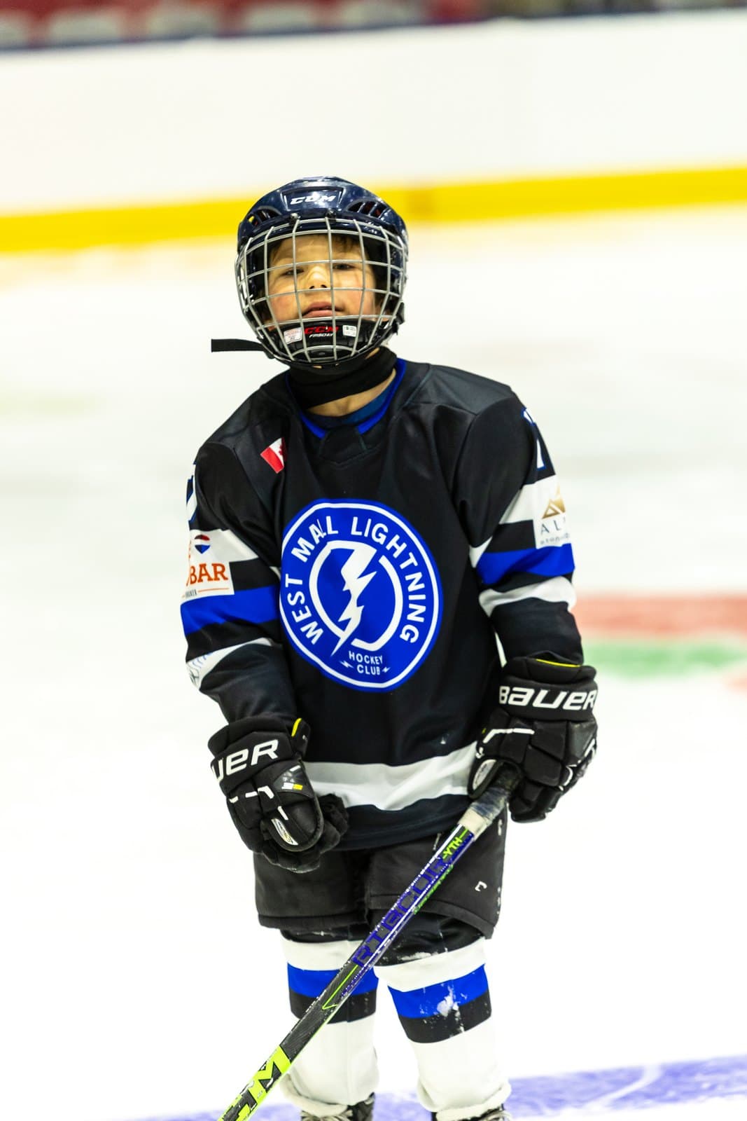 A young skater takes the puck up ice with careful, deliberate strides