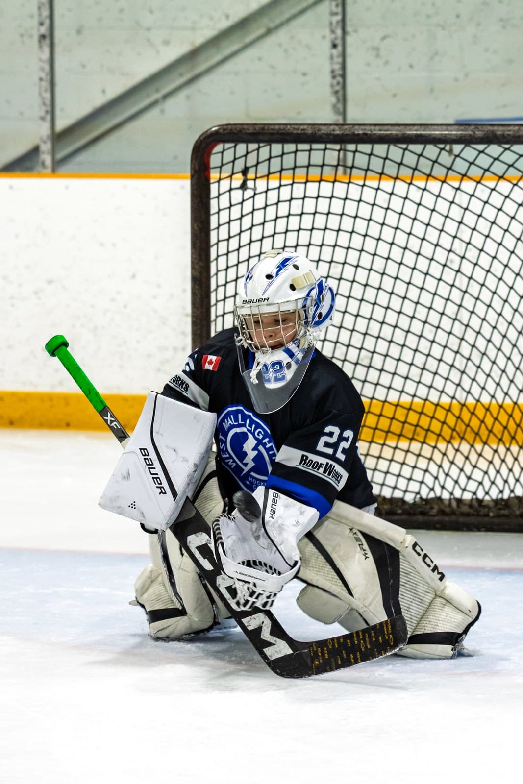 A goaltender crouched in the crease, eyes locked on an incoming shot