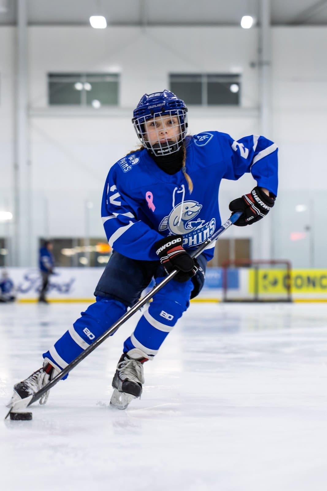 A player carries the puck with head up, scanning the ice ahead