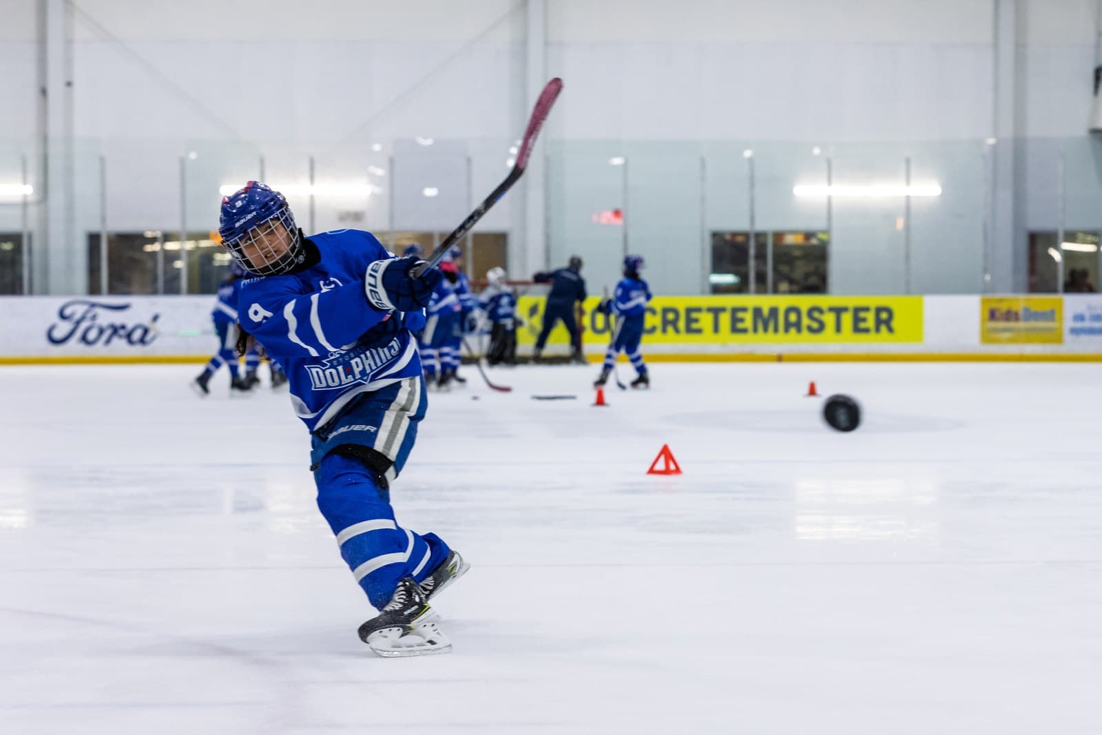 A skater leans hard into a shot, the puck just off the blade