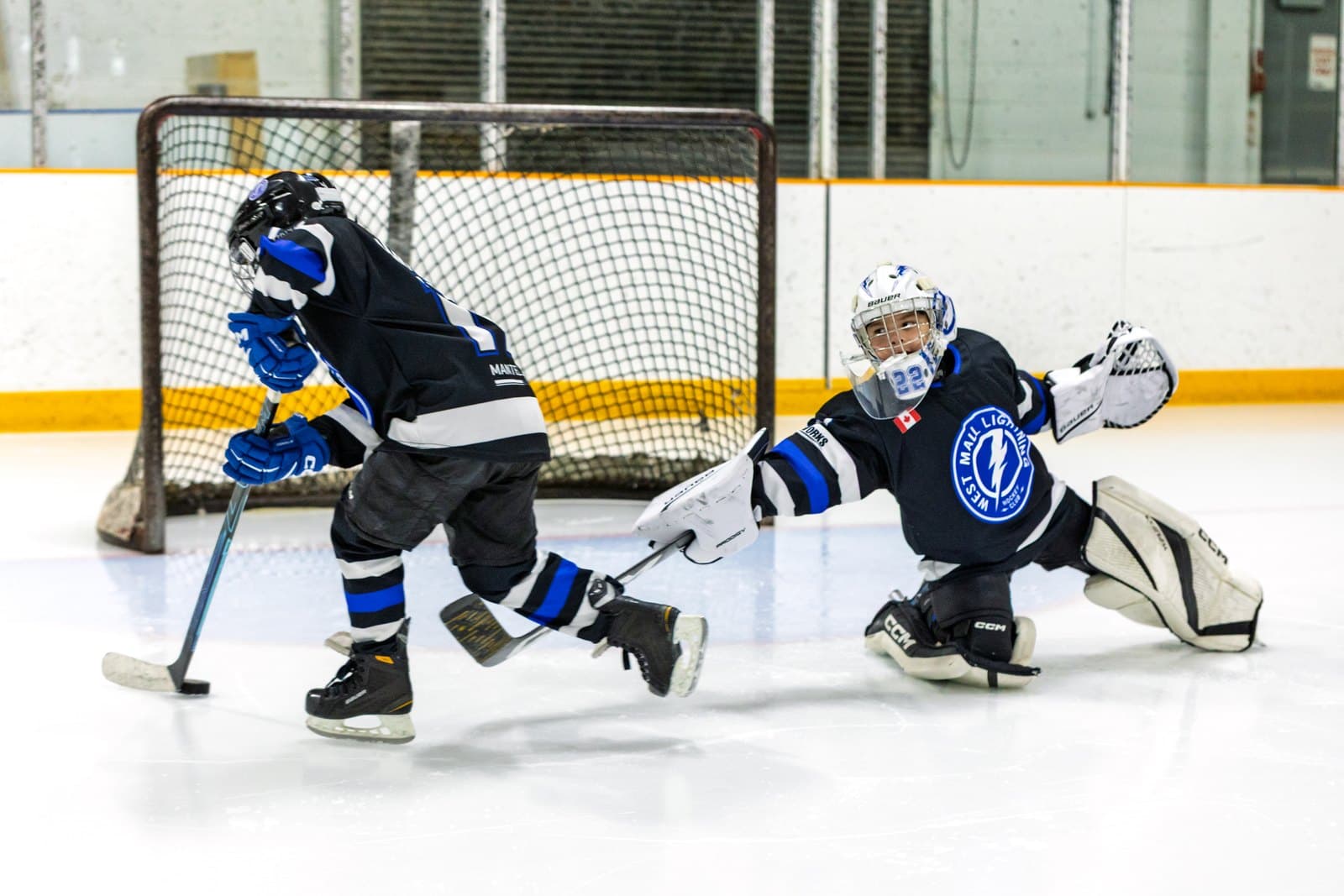 A goaltender pushes across for a point-blank save as the shooter follows through