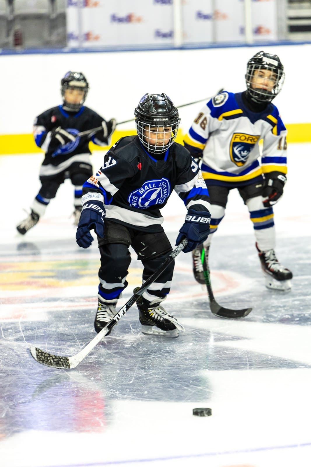 Two skaters race stride for stride toward a loose puck