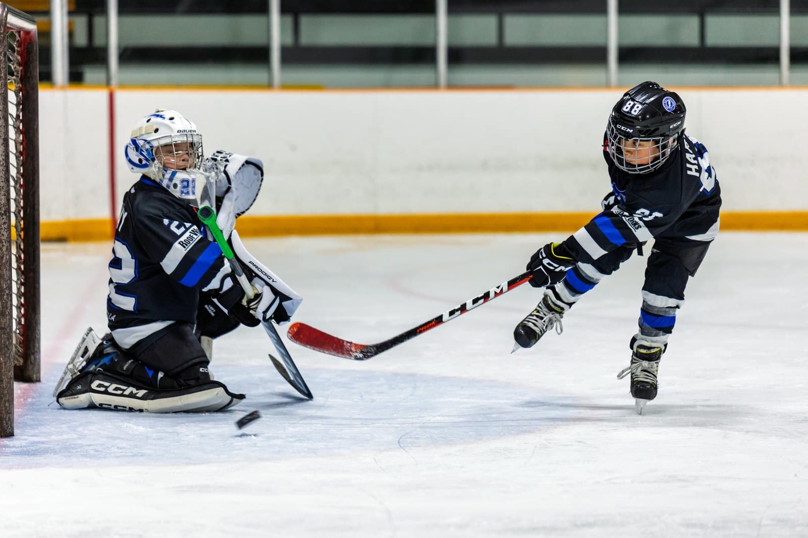A shooter cuts across the crease as the goaltender slides to cut off the angle