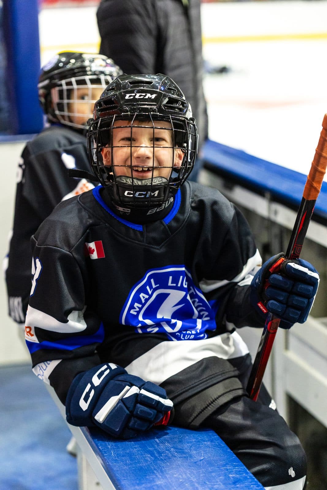 A player sits on the bench between shifts, helmet still on