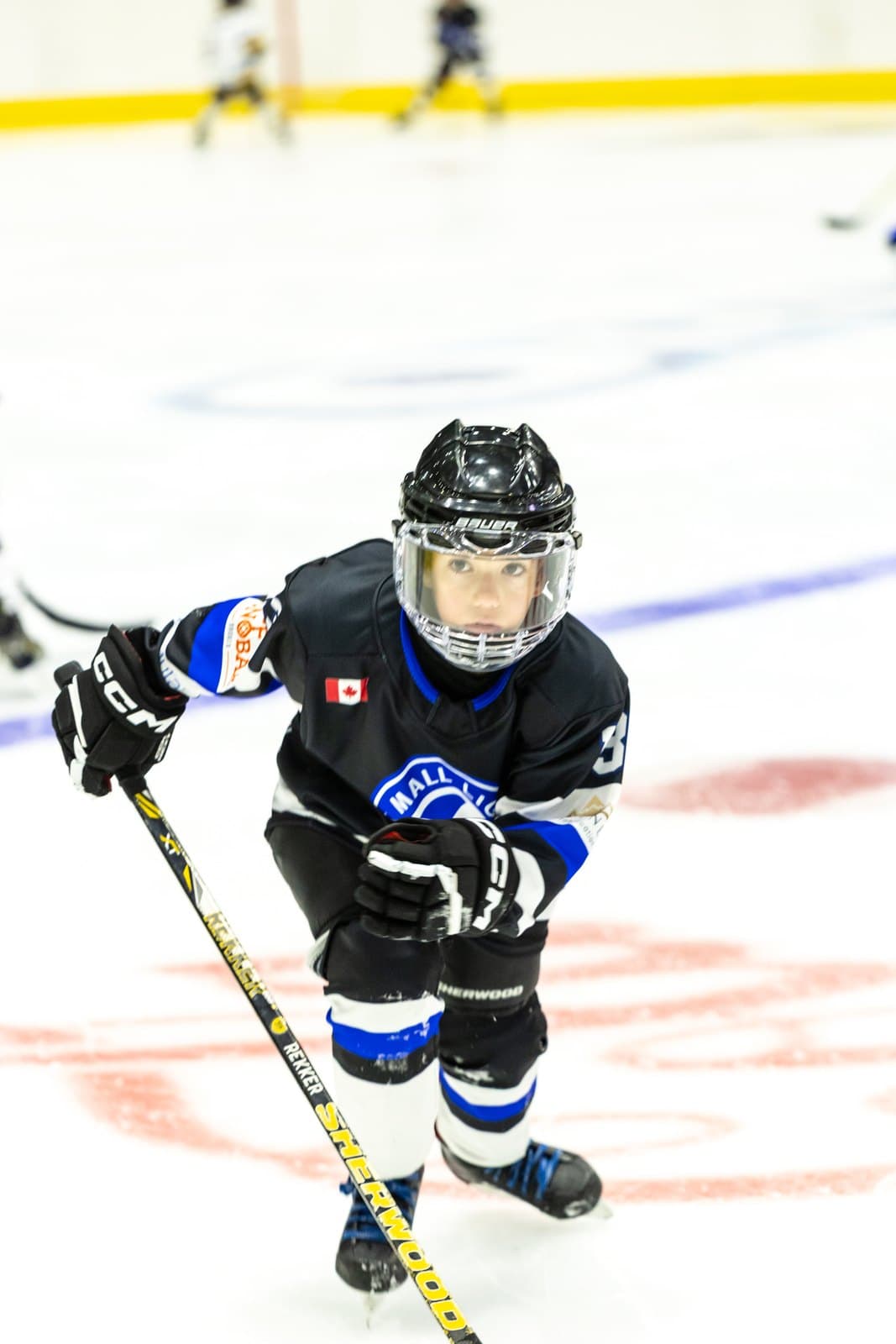 A player leans over the puck, protecting it through the middle
