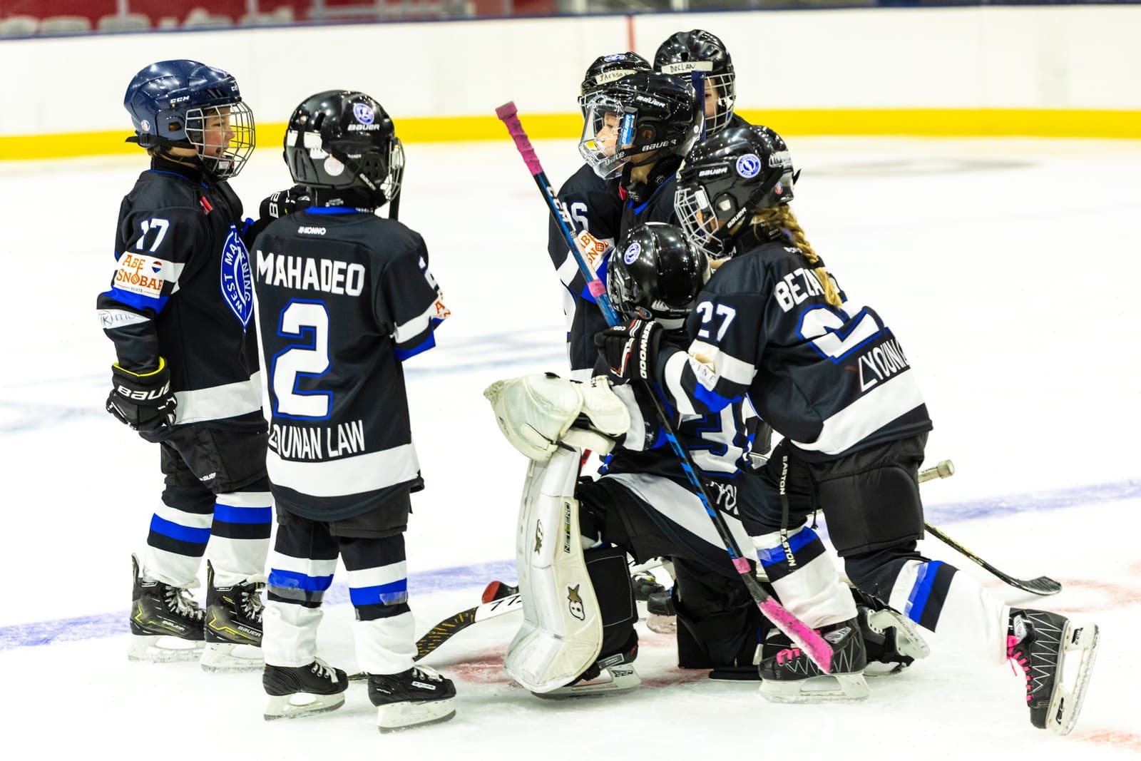 Teammates crowd around the goaltender at the net for a group photo