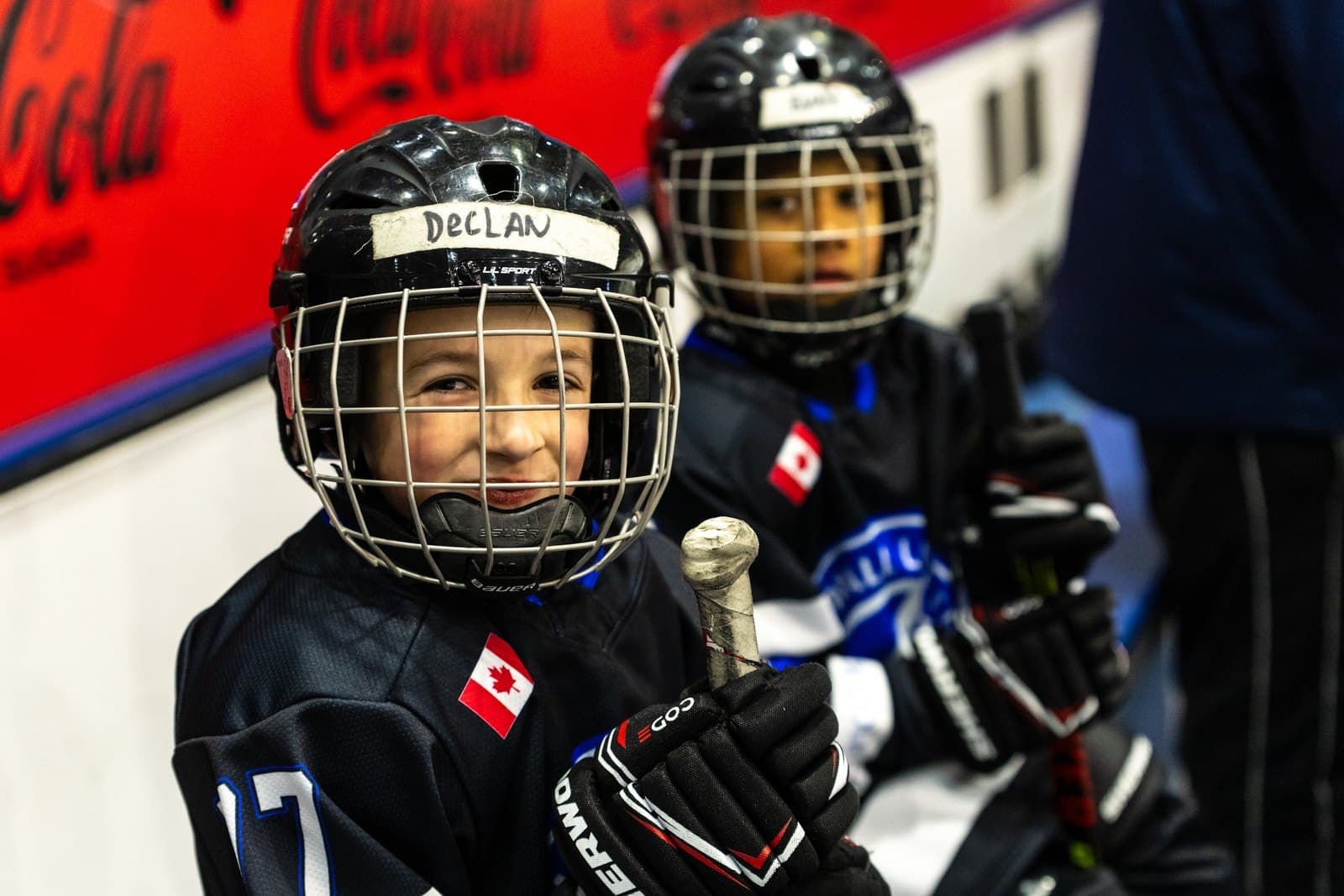 Two teammates side by side at the glass, both grinning through their cages