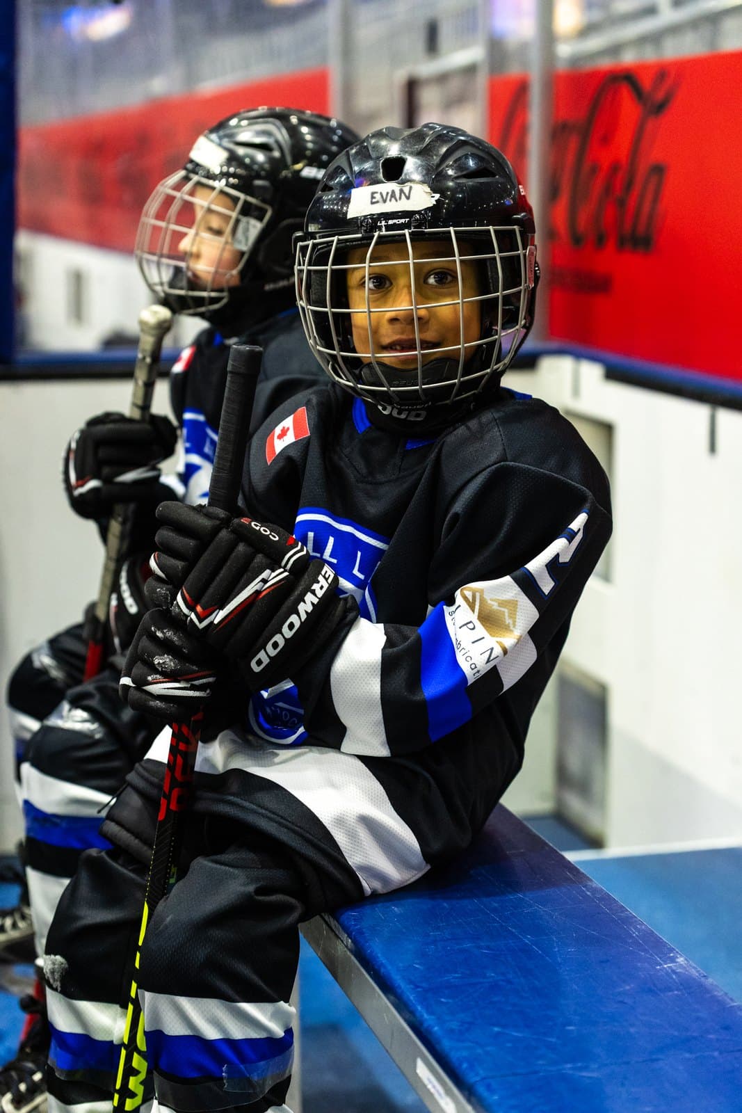 A player rests on the bench with a stick across their knees